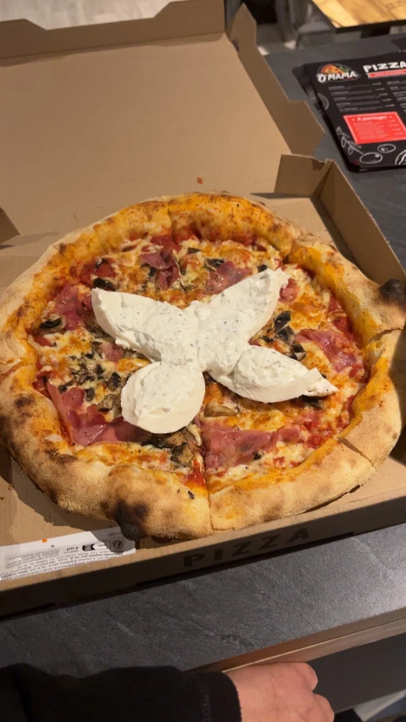 Pizza dans sa boîte de livraison, burrata déposée au centre sur la charcuterie et les champignons
